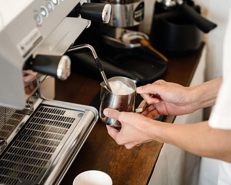 Barista steaming milk at the machine