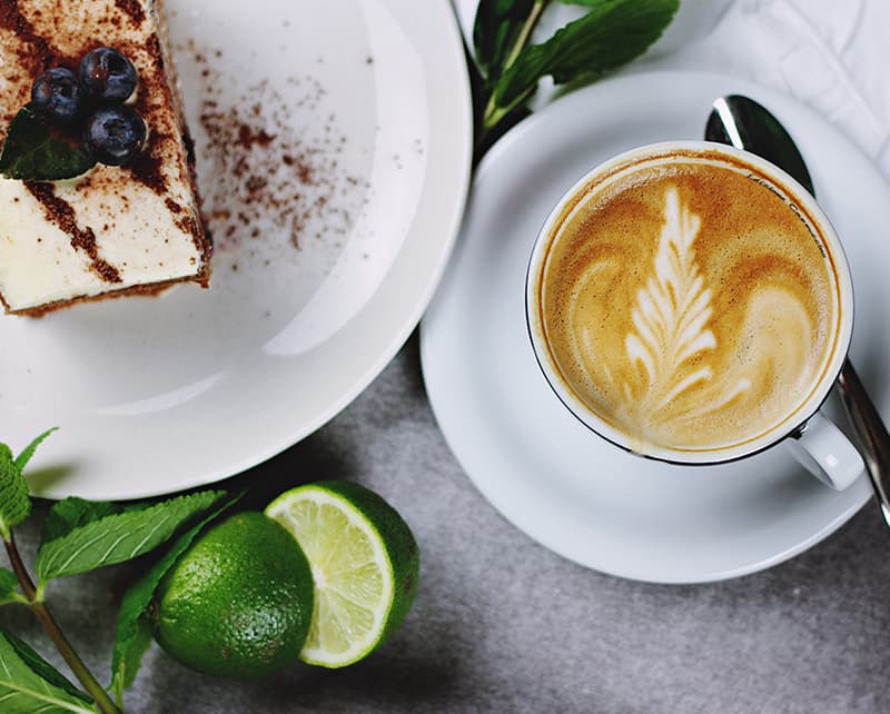 Slice of cake next to a latte